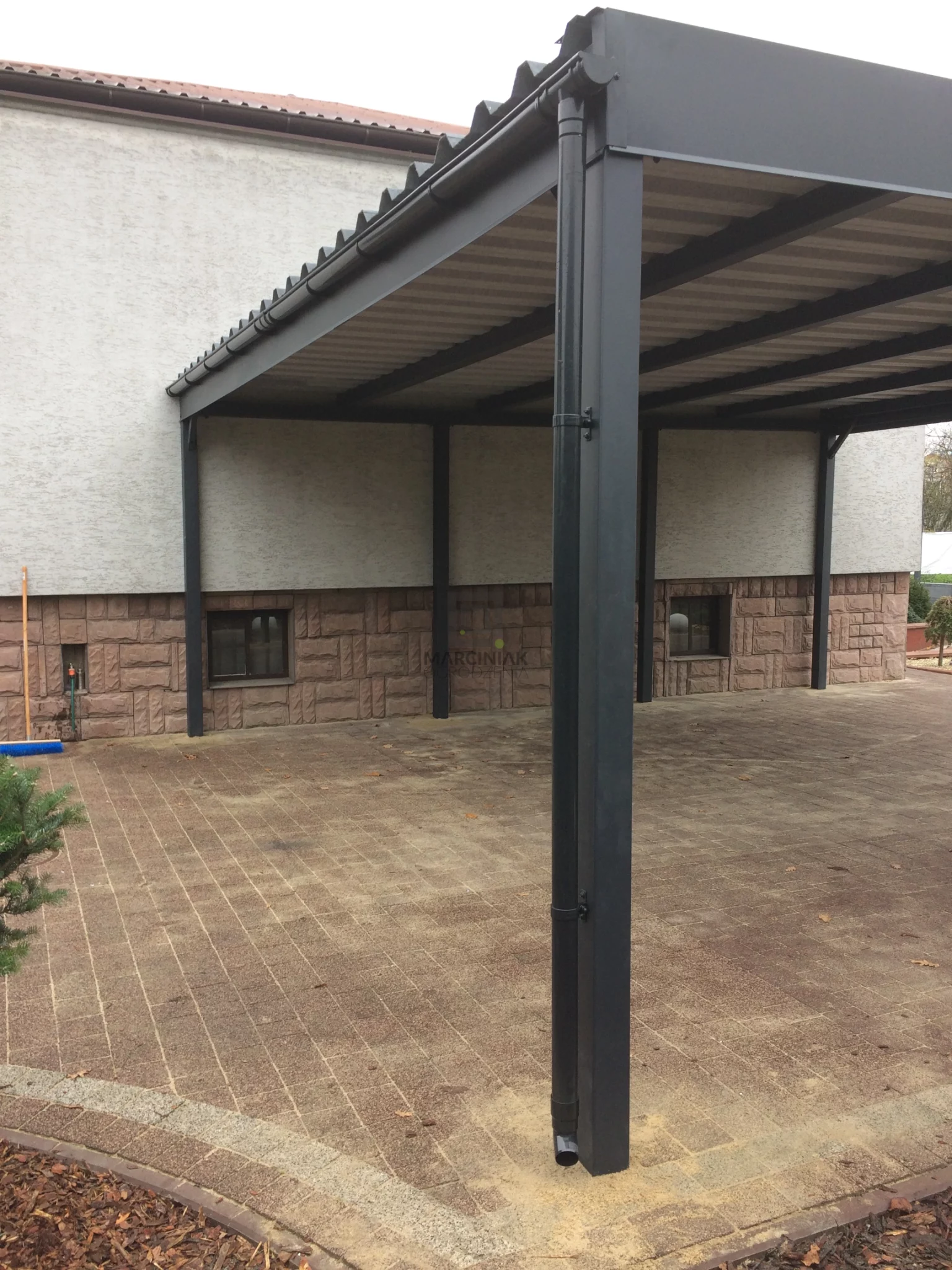 Realizacja minimalistycznego przydomowego zadaszenia bez ścianek, ustawionego na czerwonej kostce brukowej